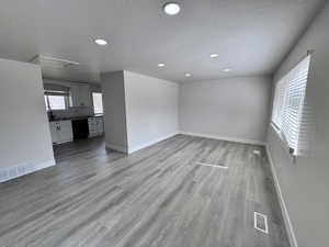 Unfurnished living room with a healthy amount of sunlight, visible vents, and light wood-type flooring