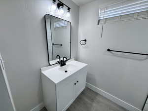 Bathroom featuring vanity, wood finished floors, and baseboards