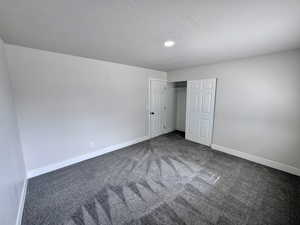 Unfurnished bedroom featuring carpet, baseboards, a closet, and a textured ceiling