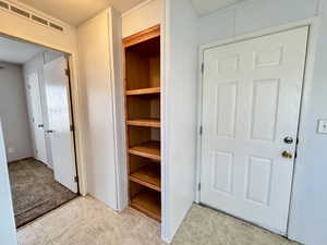 View of front door entrance, built-in storage shelves and view of Bedroom 2.