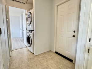 Laundry area with stacked washer/dryer. View of side door that leads to dog run.