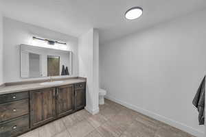 Bathroom with vanity, toilet, baseboards, and a textured ceiling