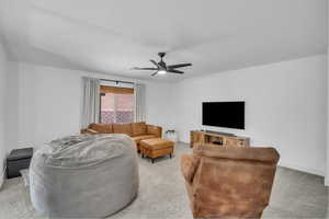 Living area with ceiling fan, a textured ceiling, baseboards, and light carpet