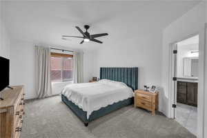 Bedroom featuring visible vents, ceiling fan, baseboards, carpet flooring, and ensuite bathroom