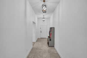 Hall featuring baseboards and an inviting chandelier