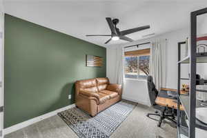 Carpeted office with visible vents, baseboards, and a ceiling fan