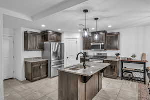 Kitchen with visible vents, dark brown cabinets, light stone counters, stainless steel appliances, and a sink