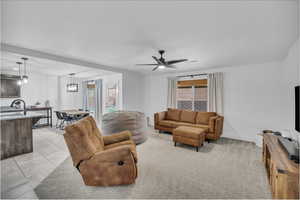 Living room featuring light tile patterned floors, a ceiling fan, and baseboards