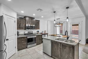 Kitchen featuring visible vents, dark brown cabinets, a center island with sink, appliances with stainless steel finishes, and a sink