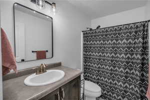 Bathroom with a shower with shower curtain, toilet, and vanity