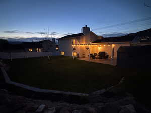 Back of house with a fenced backyard, a chimney, and a patio