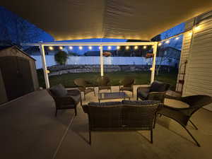 Patio at twilight with a fenced backyard, a yard, and a shed