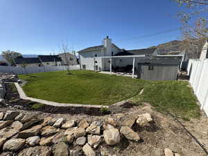 View of yard with a patio, a fenced backyard, an outbuilding, and a shed