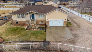 View of front facade featuring a garage, brick siding, fence private yard, and a front yard