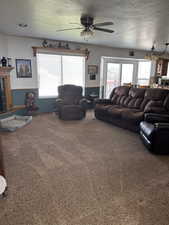 Living room with ceiling fan, carpet flooring, and a healthy amount of sunlight