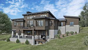 Rear view of house with a yard, a standing seam roof, a balcony, and stone siding