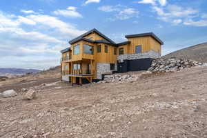 Back of property with stone siding and a deck with mountain view