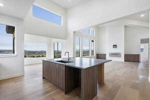 Kitchen featuring modern cabinets, an island with sink, open floor plan, light wood finished floors, and healthy amount of natural light