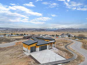 View of front facade featuring stone siding, a mountain view, an attached garage, and driveway