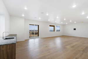 Unfurnished living room with light wood-type flooring, healthy amount of natural light, and recessed lighting