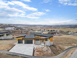 Contemporary house with stone siding, concrete driveway, a mountain view, and an attached garage