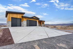 Contemporary home with stone siding, a mountain view, concrete driveway, and an attached garage