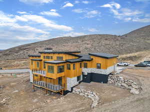 Rear view of property featuring a deck with mountain view and stone siding