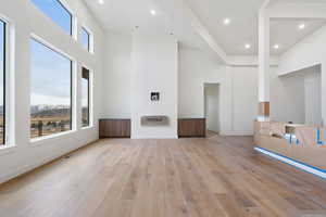 Unfurnished living room featuring light wood-style floors, a high ceiling, recessed lighting, and a mountain view