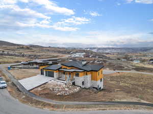 View of front of home featuring stone siding, concrete driveway, a mountain view, and a porch