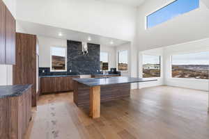 Kitchen featuring modern cabinets, wood finish cabinetry, an island with sink, a kitchen breakfast bar, and light wood finished floors