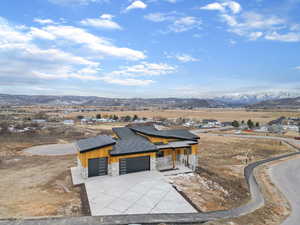 View of front of property featuring stone siding, a mountain view, a garage, and driveway