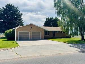 Single story home with a garage, brick siding, concrete driveway, and a front yard