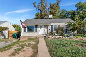 View of front of property with a shingled roof and fence