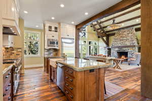 Kitchen featuring a stone fireplace, dark wood-style floors, tasteful backsplash, and built in appliances