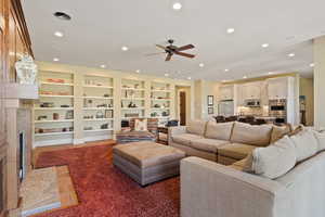 Living room featuring a ceiling fan, a fireplace with flush hearth, recessed lighting, and built in features