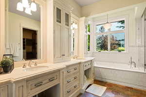 Bathroom with a sink, a notable chandelier, a garden tub, and double vanity