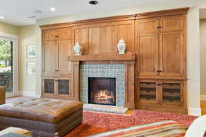 Living room with visible vents, recessed lighting, a warm lit fireplace, and baseboards