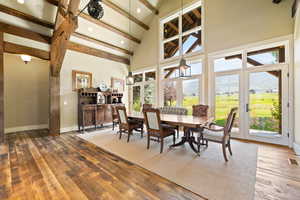 Dining space with hardwood / wood-style floors, beam ceiling, a high ceiling, and a wealth of natural light