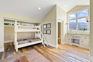 Bedroom featuring multiple windows, lofted ceiling, baseboards, and light wood-style flooring