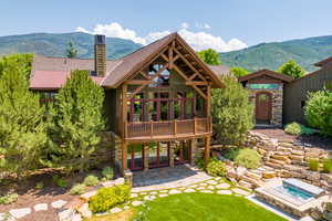 Rear view of house featuring a chimney, french doors, stone siding, a jacuzzi, and a mountain view