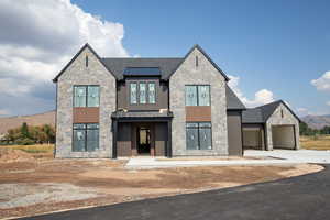 View of front of home featuring a standing seam roof, a mountain view, stone siding, a metal roof, and concrete driveway