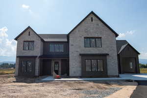 Modern farmhouse with board and batten siding, a standing seam roof, stone siding, a metal roof, and a mountain view