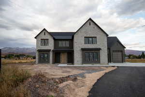 View of front of home with stone siding, a mountain view, board and batten siding, and driveway