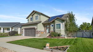 View of front facade with stucco siding, driveway, an attached garage, solar panels, and a gate