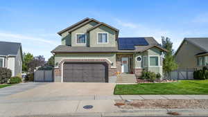 Craftsman-style house featuring stucco siding, an attached garage, driveway, solar panels, and brick siding