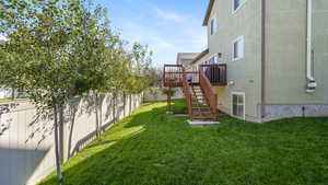 Fenced backyard featuring stairs and a wooden deck