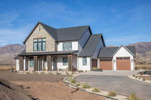 Modern farmhouse with a mountain view, covered porch, driveway, a standing seam roof, and roof with shingles