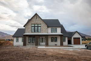 View of front of home featuring a porch, board and batten siding, a mountain view, a shingled roof, and stone siding