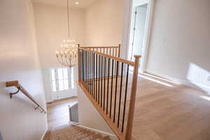 Staircase with a chandelier, wood finished floors, and a high ceiling