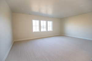 Empty room with light colored carpet and baseboards